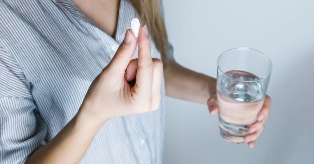 Medicine - Woman Holding Half-full Glass and White Medicine Pill