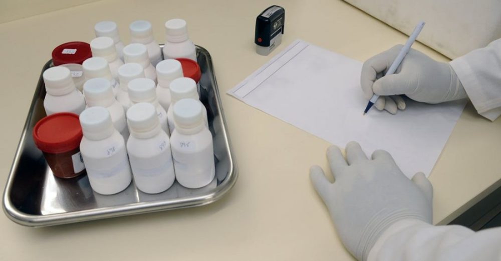 Laboratory - Person in White Hand Gloves Writing on White Paper