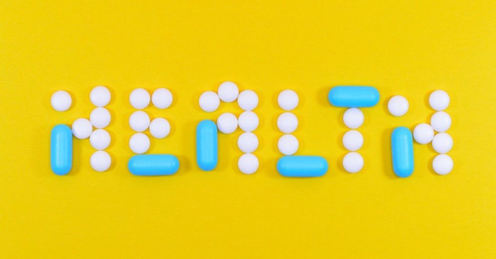 Medicine - White and Blue Health Pill and Tablet Letter Cutout on Yellow Surface