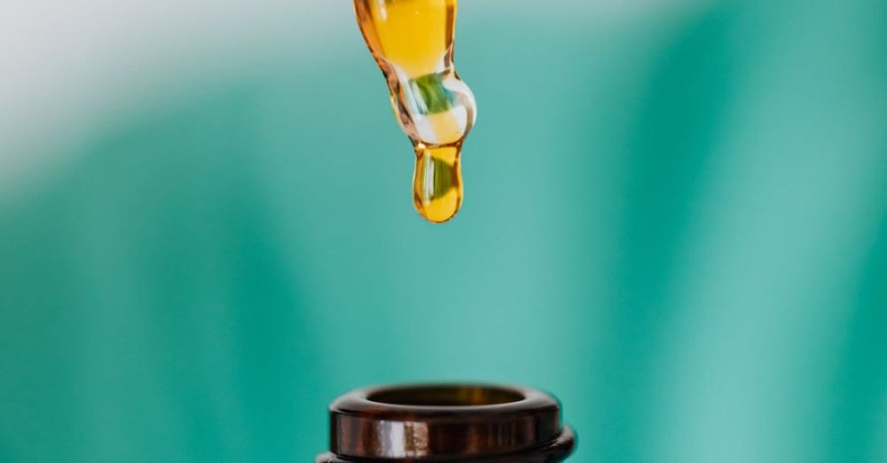 Scientific Research - Closeup of anonymous doctor with pipette for fluid dripping yellow medication in brown glass vial while making procedure in clinic