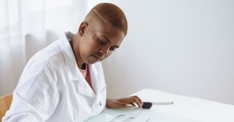 Scientific Research - Focused African American teenage chemist working on formula in scientific center